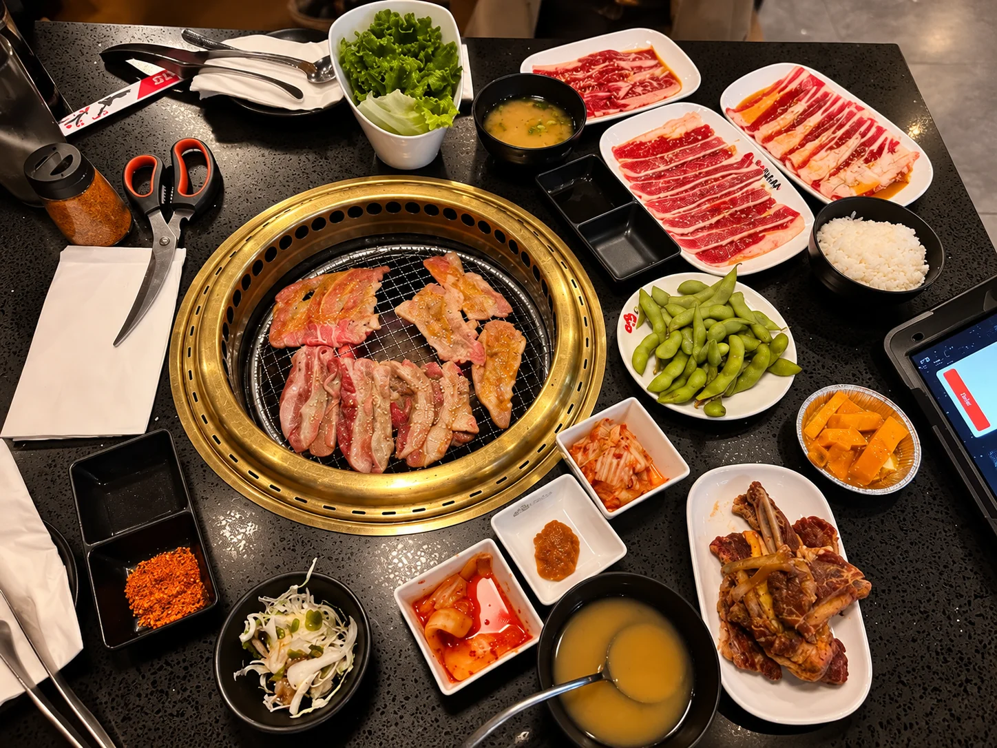 Beef on the grill surrounded by meats and sides